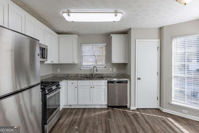 kitchen with dark stone countertops, white cabinets, a textured ceiling, and appliances with stainless steel finishes