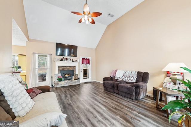 living room featuring vaulted ceiling, hardwood / wood-style flooring, a stone fireplace, and ceiling fan