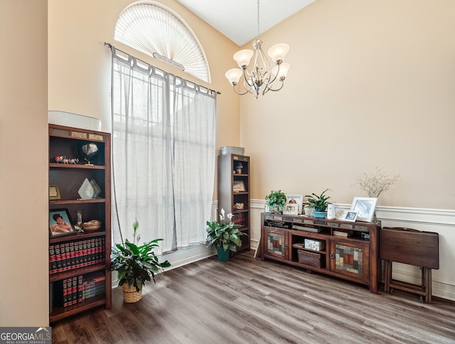 sitting room featuring wood-type flooring, vaulted ceiling, and an inviting chandelier