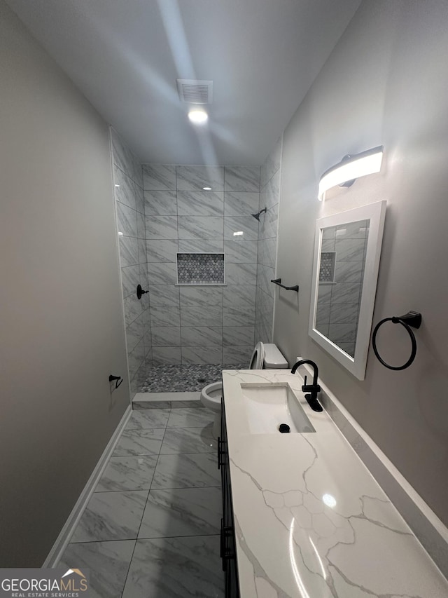 bathroom featuring toilet, vanity, and tiled shower