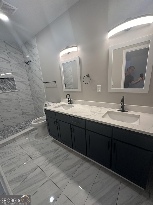 bathroom with toilet, vanity, and tiled shower