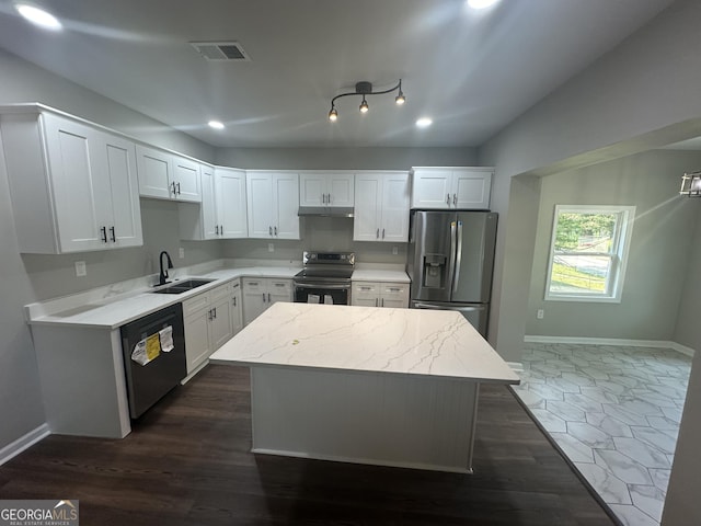 kitchen featuring appliances with stainless steel finishes, light stone counters, sink, a center island, and white cabinetry