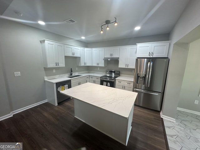 kitchen with light stone countertops, white cabinetry, sink, stainless steel appliances, and a kitchen island