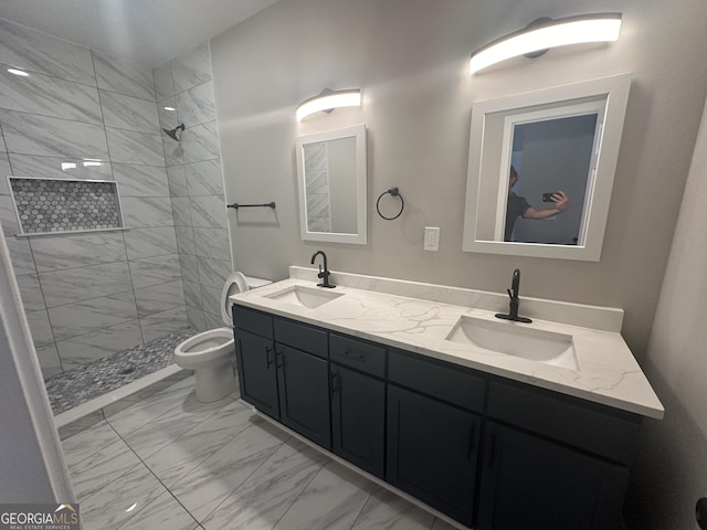 bathroom with tiled shower, vanity, and toilet