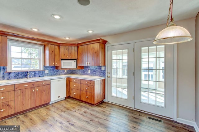 kitchen featuring sink, tasteful backsplash, decorative light fixtures, white appliances, and light wood-type flooring