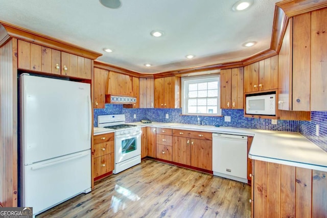 kitchen with light wood-type flooring, custom range hood, white appliances, crown molding, and sink