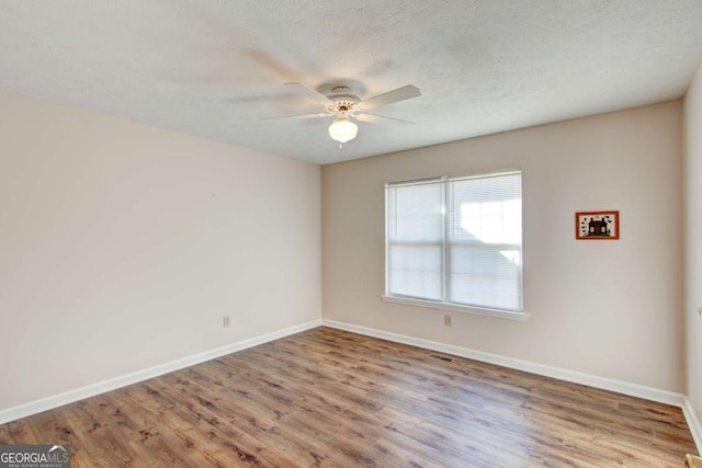 spare room featuring hardwood / wood-style flooring, ceiling fan, and a textured ceiling