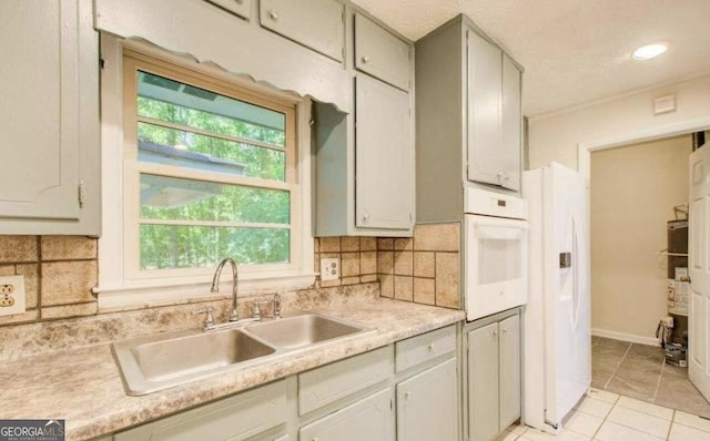 kitchen with decorative backsplash, sink, light tile patterned floors, and white appliances