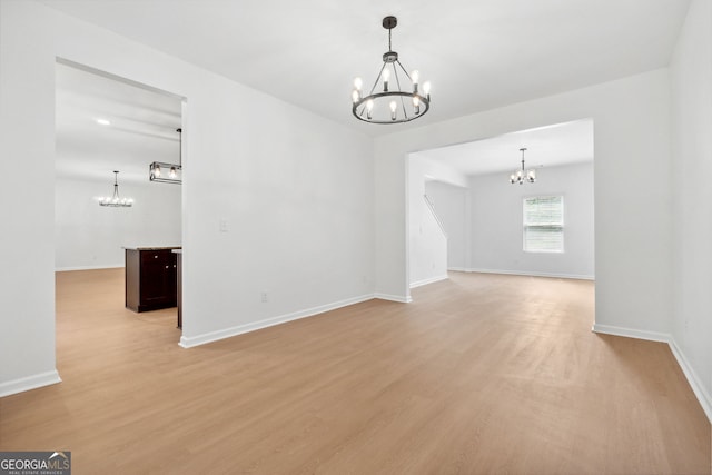 spare room featuring a chandelier and light hardwood / wood-style flooring