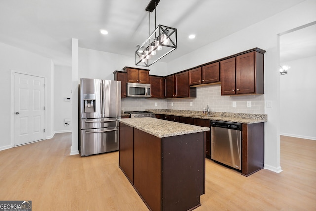 kitchen featuring a kitchen island, appliances with stainless steel finishes, dark brown cabinets, and decorative light fixtures