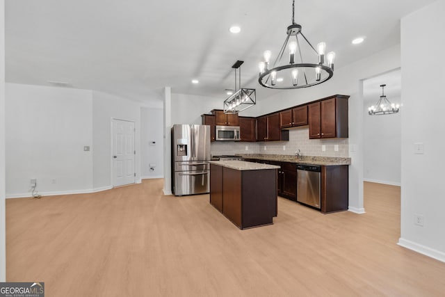 kitchen with an inviting chandelier, light wood-type flooring, pendant lighting, stainless steel appliances, and backsplash