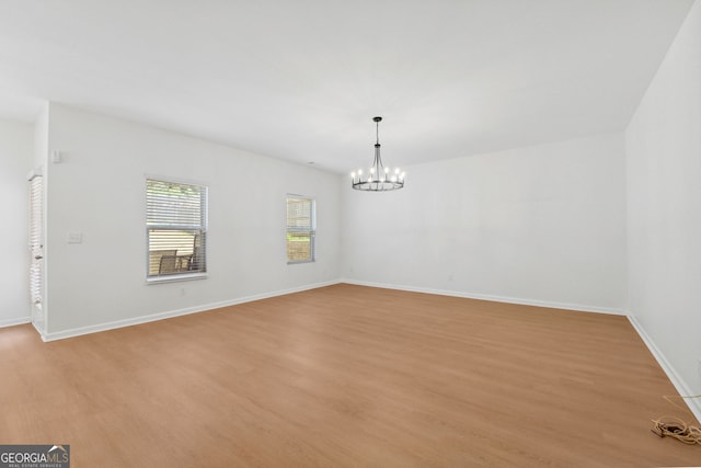 spare room featuring an inviting chandelier and light wood-type flooring