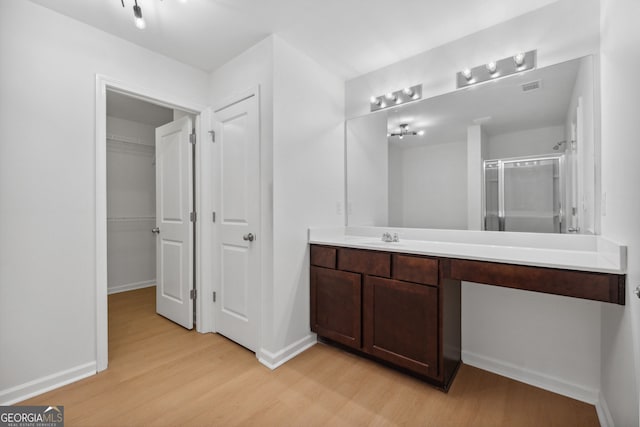 bathroom with hardwood / wood-style flooring, vanity, and a shower with shower door