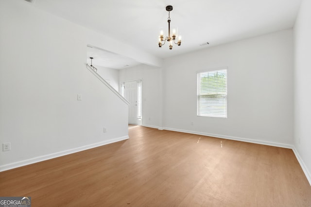 unfurnished room with an inviting chandelier and hardwood / wood-style flooring