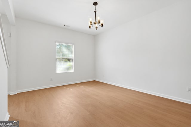 spare room with a chandelier and light hardwood / wood-style flooring