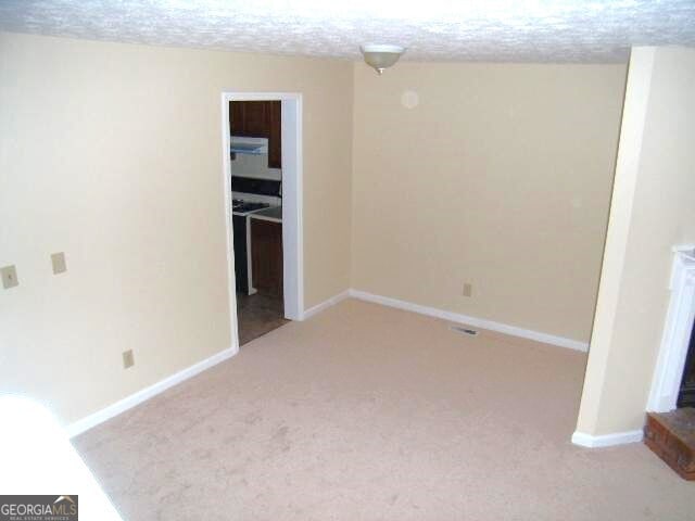 unfurnished room with a textured ceiling and light colored carpet