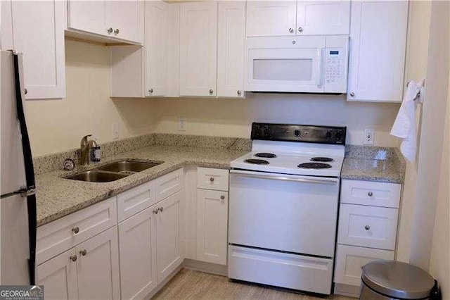 kitchen with white appliances, light stone countertops, sink, and white cabinets