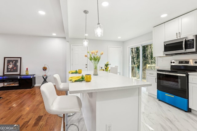 kitchen with a kitchen breakfast bar, stainless steel appliances, decorative light fixtures, white cabinets, and a center island