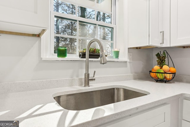 details featuring light stone counters, sink, and white cabinets