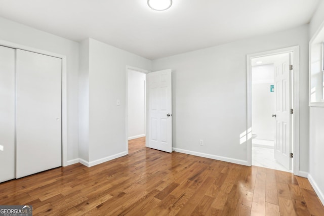 unfurnished bedroom featuring connected bathroom, light hardwood / wood-style flooring, and a closet