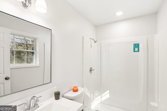 bathroom featuring a shower, vanity, and toilet