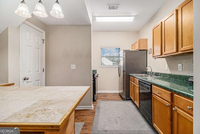 kitchen with hardwood / wood-style floors, sink, hanging light fixtures, and appliances with stainless steel finishes