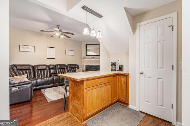 kitchen with pendant lighting, a breakfast bar, dark hardwood / wood-style floors, ceiling fan, and kitchen peninsula