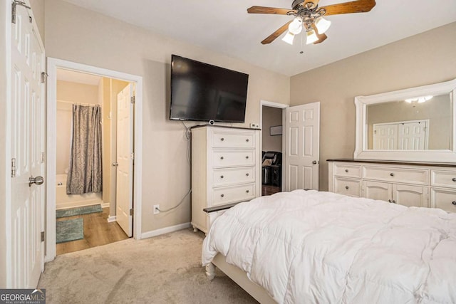 bedroom with ensuite bathroom, ceiling fan, and light colored carpet