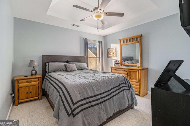 carpeted bedroom featuring ceiling fan and a tray ceiling