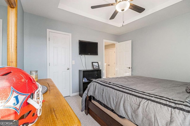 carpeted bedroom featuring a raised ceiling and ceiling fan