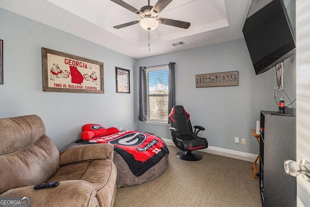 carpeted bedroom with a raised ceiling and ceiling fan