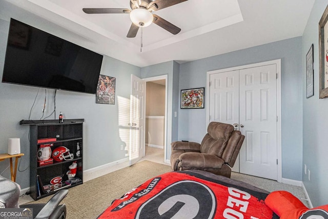 interior space with a tray ceiling, ceiling fan, and carpet floors