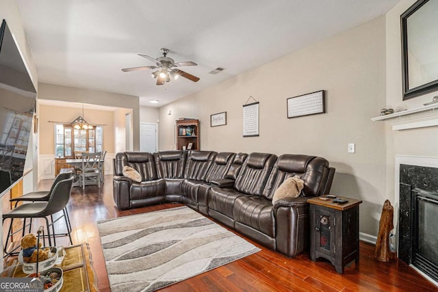 living room with ceiling fan with notable chandelier, dark hardwood / wood-style flooring, and a premium fireplace