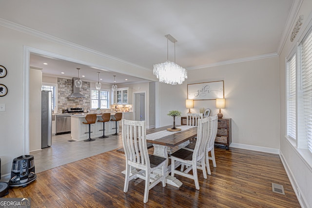 dining area with dark hardwood / wood-style flooring, an inviting chandelier, and ornamental molding