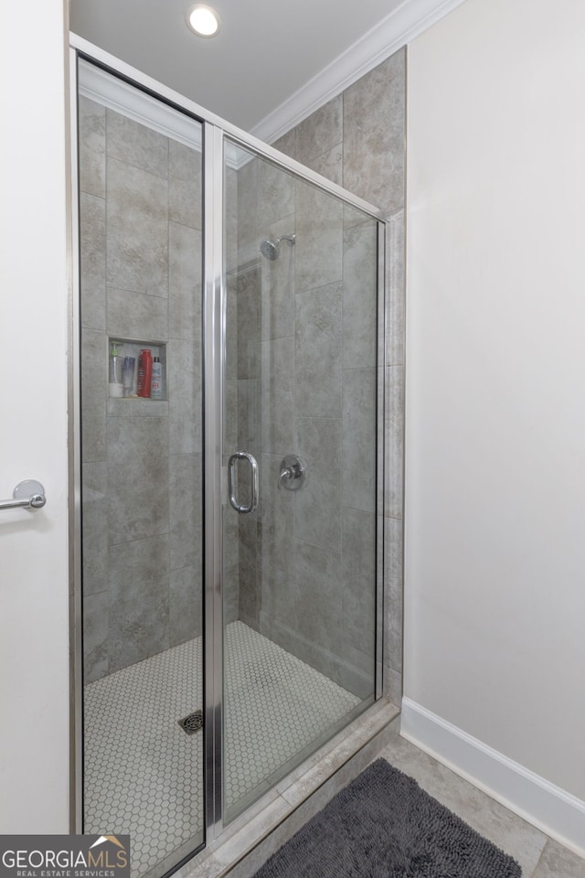 bathroom featuring tile patterned floors, a shower with door, and crown molding