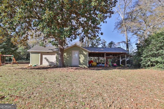 back of house featuring a lawn, a carport, an outbuilding, and a playground