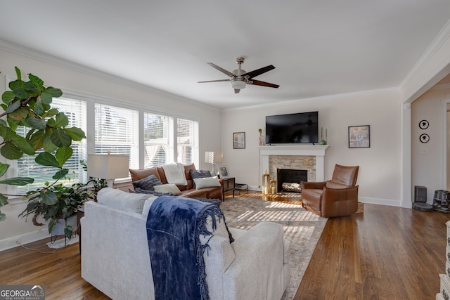 living room with a fireplace, ornamental molding, ceiling fan, and dark wood-type flooring