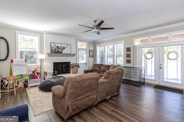 living room featuring ceiling fan, plenty of natural light, crown molding, and a brick fireplace