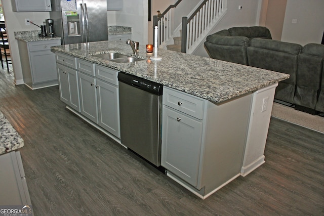 kitchen with stainless steel dishwasher, a center island with sink, fridge with ice dispenser, and gray cabinetry