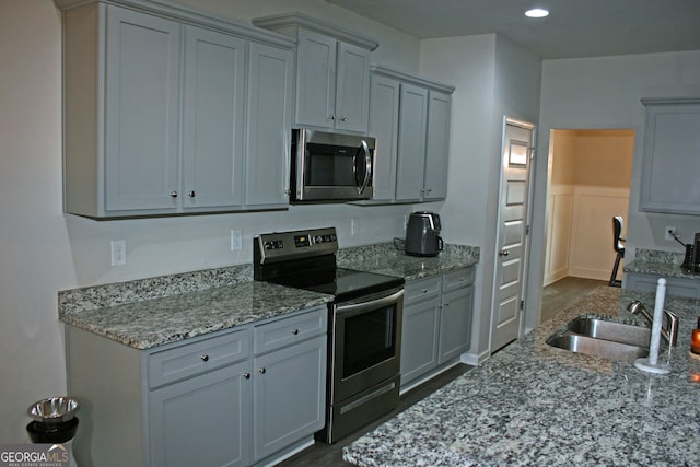 kitchen with sink, stainless steel appliances, gray cabinets, and light stone countertops