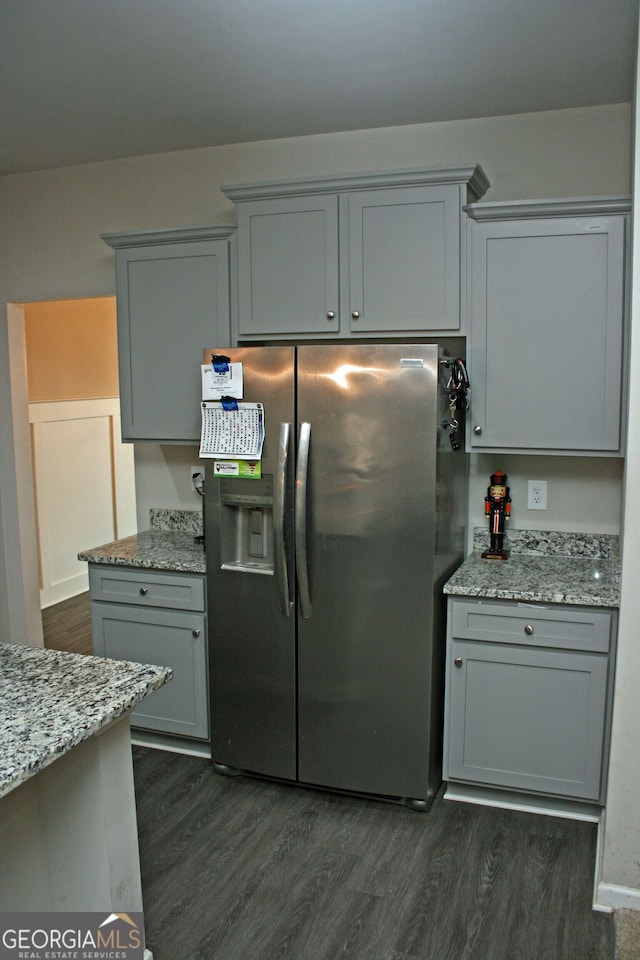 kitchen featuring dark wood-type flooring, gray cabinetry, light stone counters, and stainless steel fridge