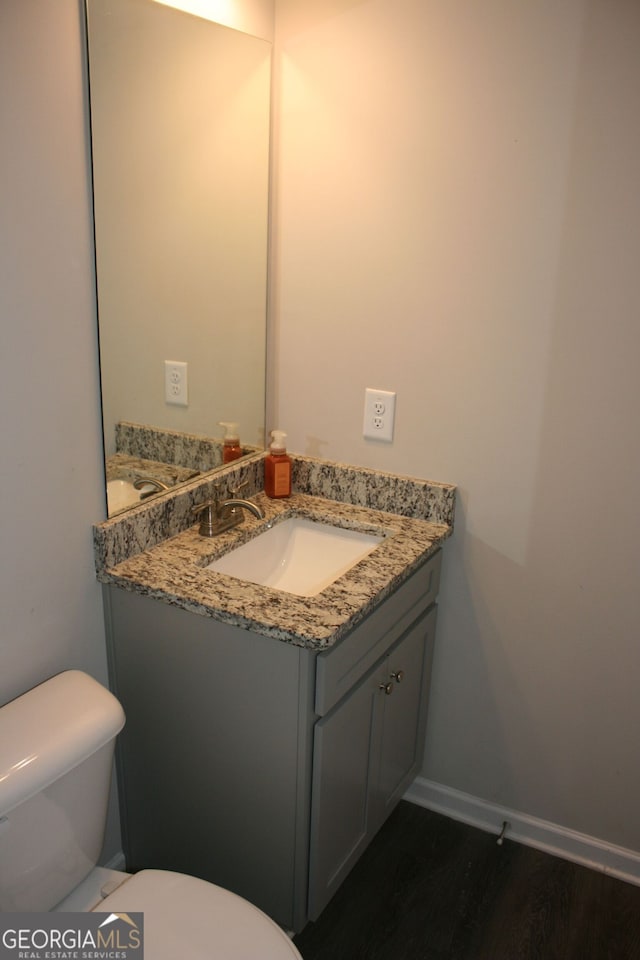 bathroom with toilet, vanity, and hardwood / wood-style floors