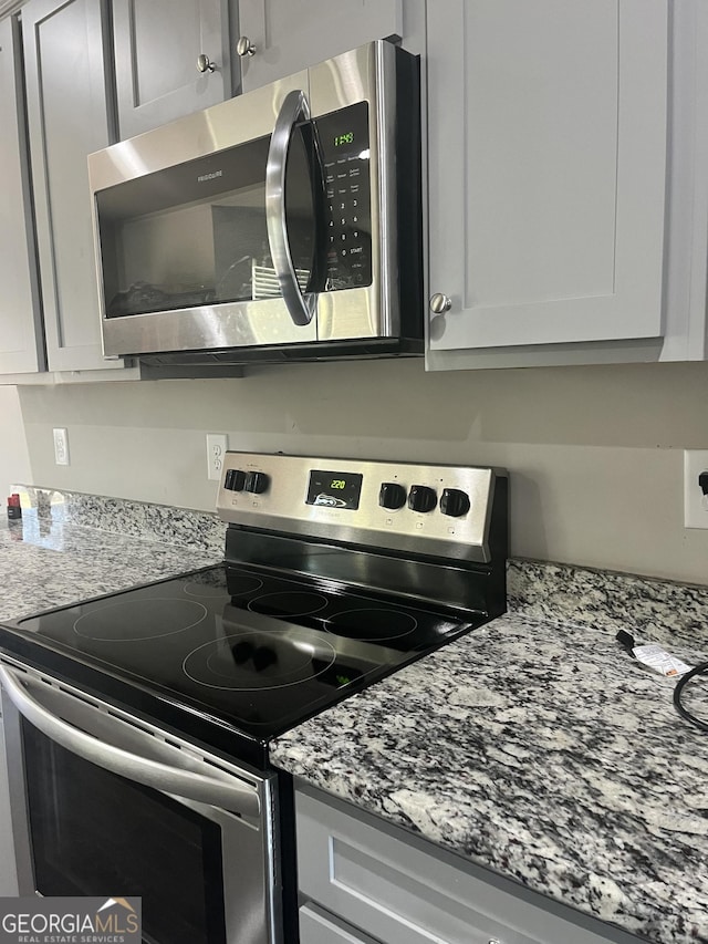 kitchen with light stone countertops and appliances with stainless steel finishes