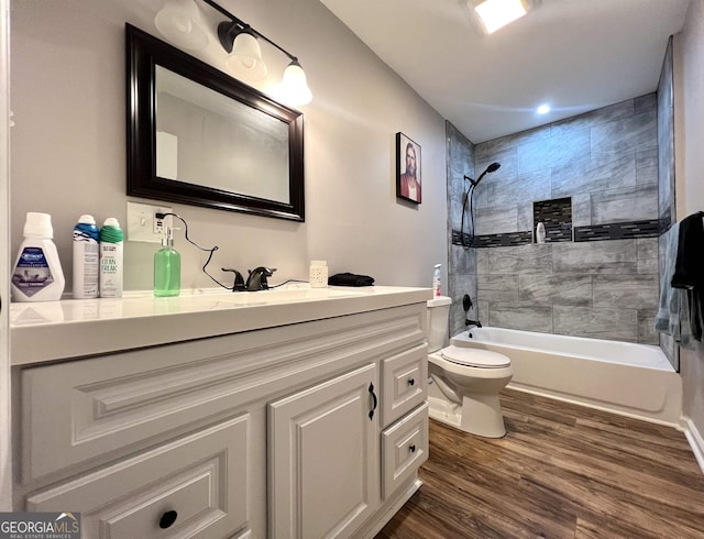 full bathroom with vanity, hardwood / wood-style floors, tiled shower / bath combo, and toilet