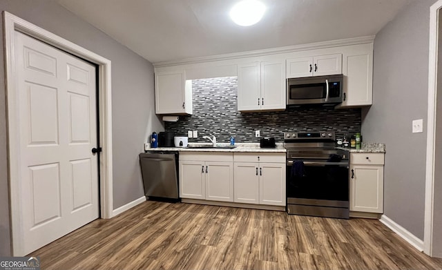 kitchen featuring white cabinets, stainless steel appliances, tasteful backsplash, and hardwood / wood-style flooring