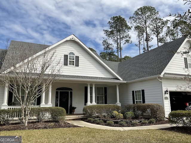 view of front of property with covered porch, roof with shingles, and a garage