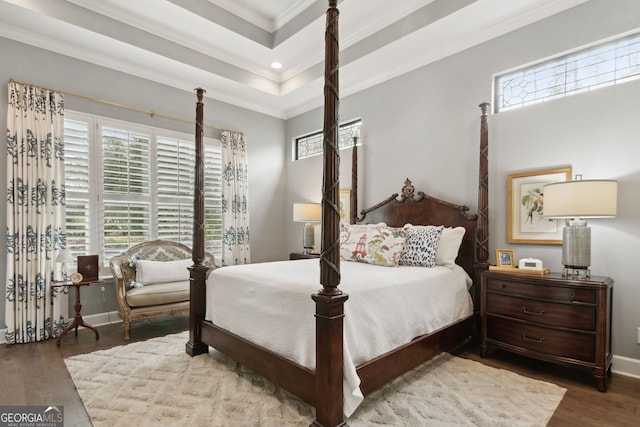 bedroom featuring ornamental molding, wood-type flooring, and a raised ceiling