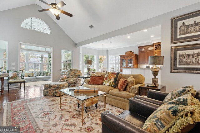 living room with ceiling fan with notable chandelier, hardwood / wood-style floors, ornate columns, and a healthy amount of sunlight