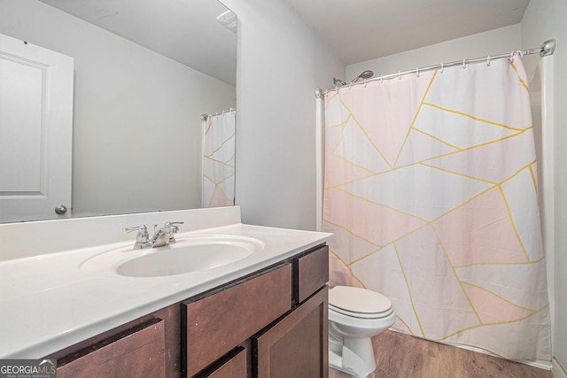 bathroom with hardwood / wood-style flooring, vanity, a shower with curtain, and toilet