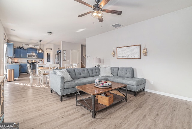 living room featuring sink, light hardwood / wood-style floors, and ceiling fan